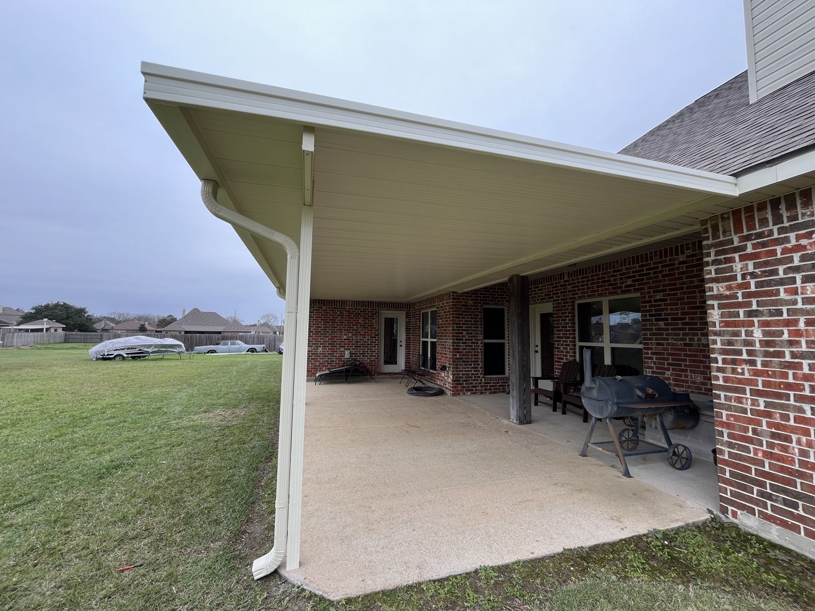Aluminum patio cover with white columns over a concrete slab