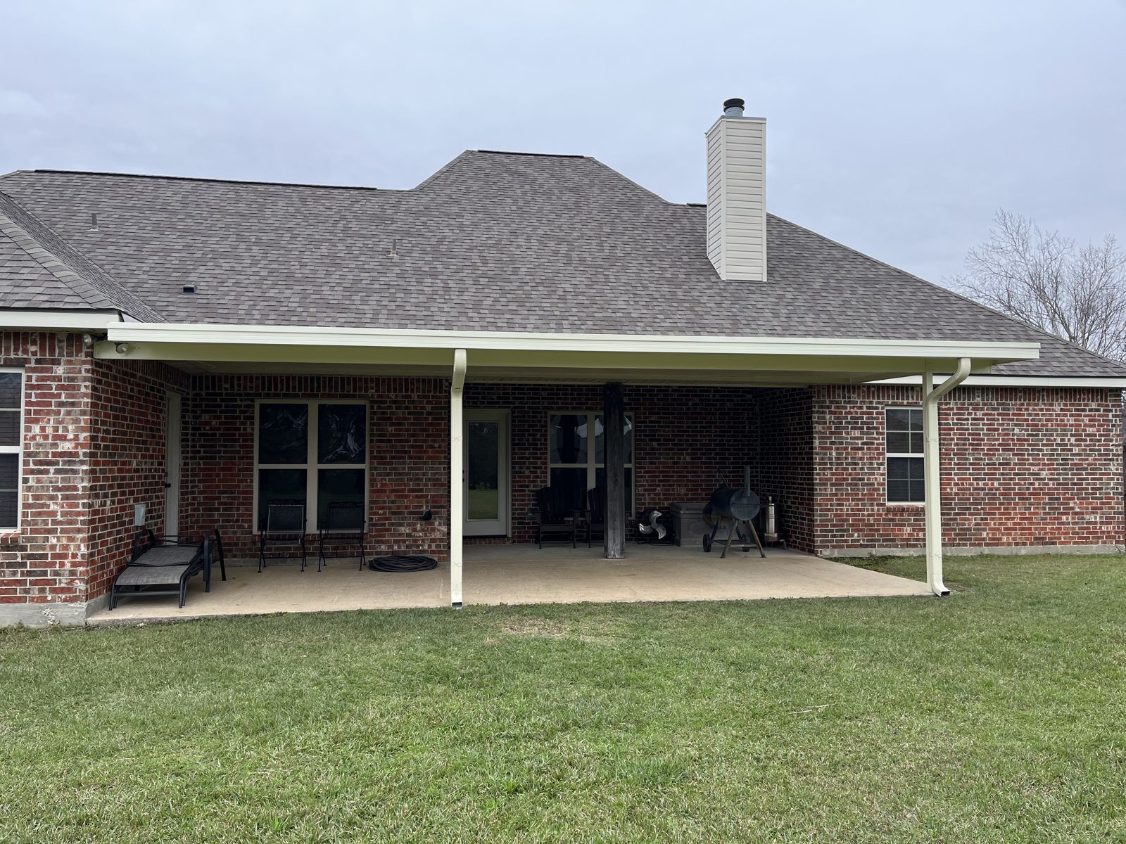 Long aluminum patio cover across the back of a brick home