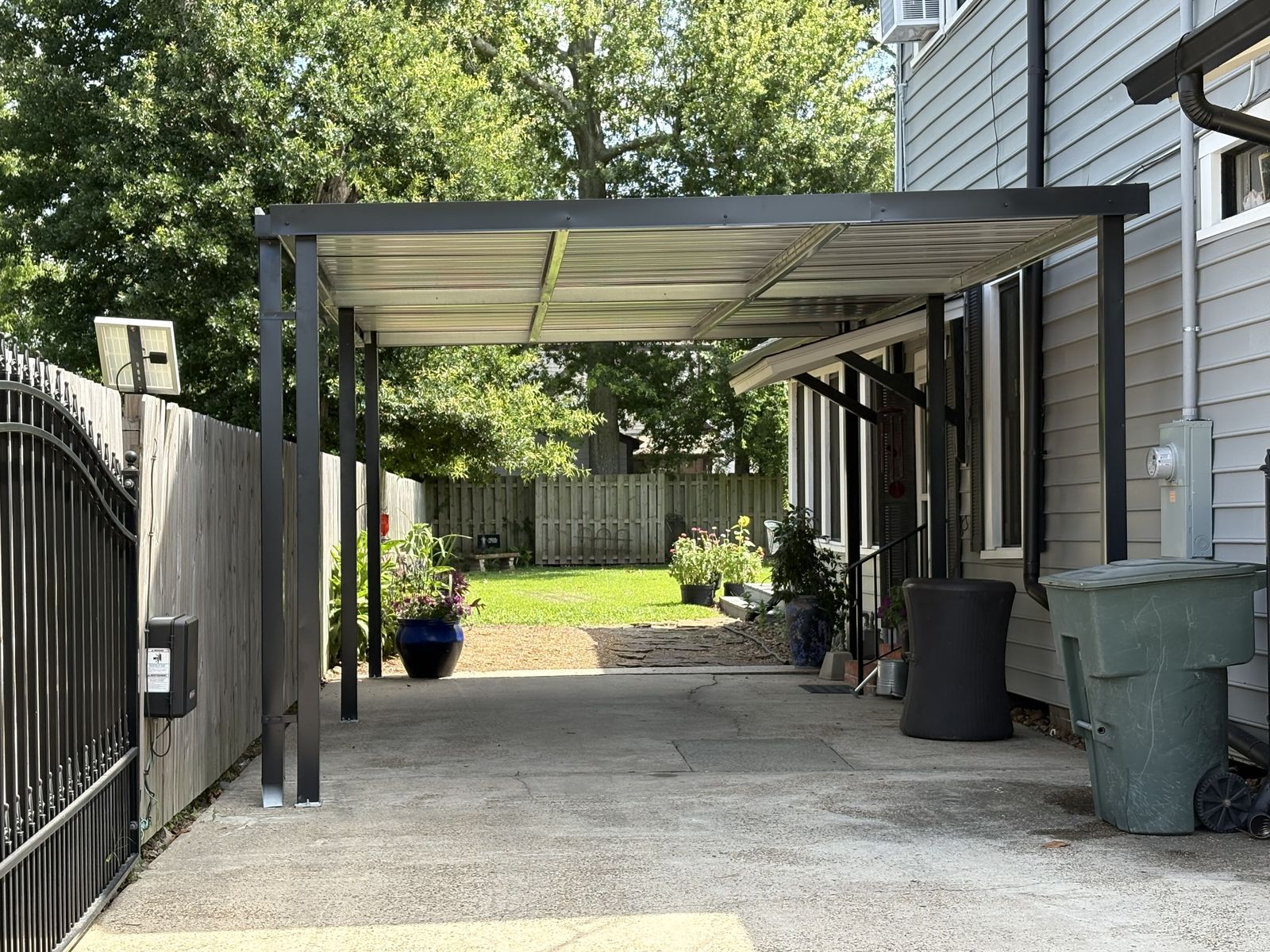 Black-post metal carport along the side of a house