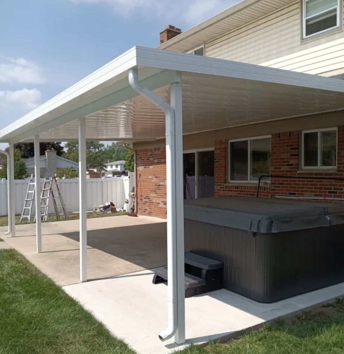 White aluminum patio cover over a hot tub on a brick home
