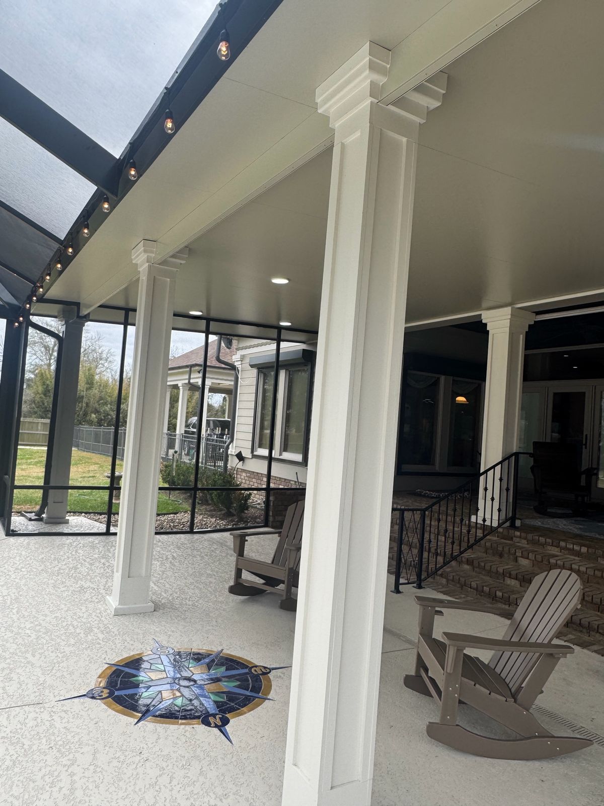 White-columned covered patio with string lights and a dark screen wall