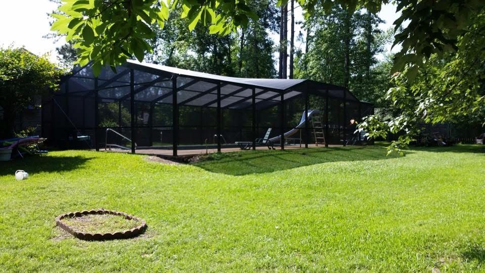 Long dark bronze pool screen enclosure in a wooded back yard