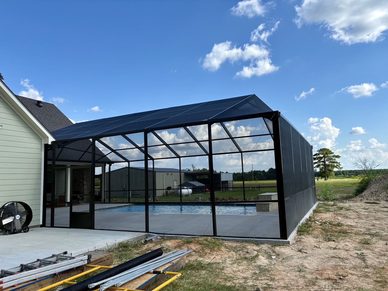 Pool enclosure with angled screen roof under blue sky