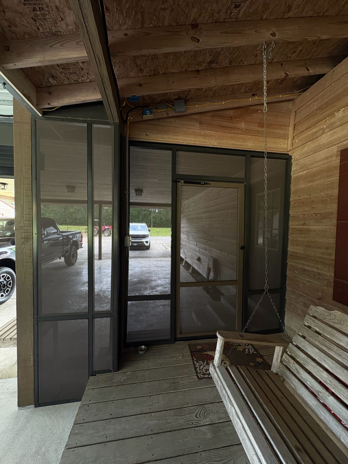 Screened porch interior with a porch swing and screen door