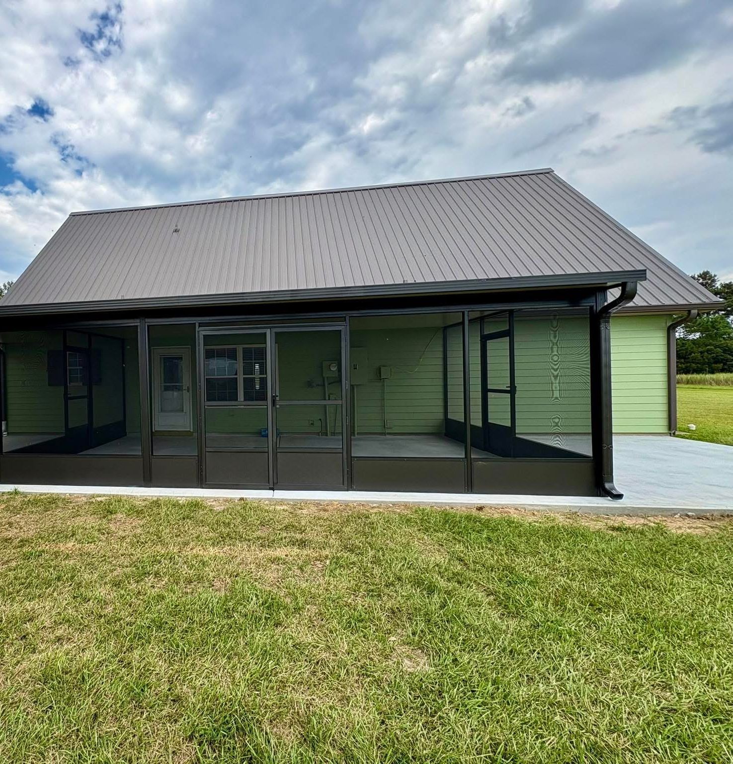 Dark bronze screened porch on a green outbuilding with metal roof