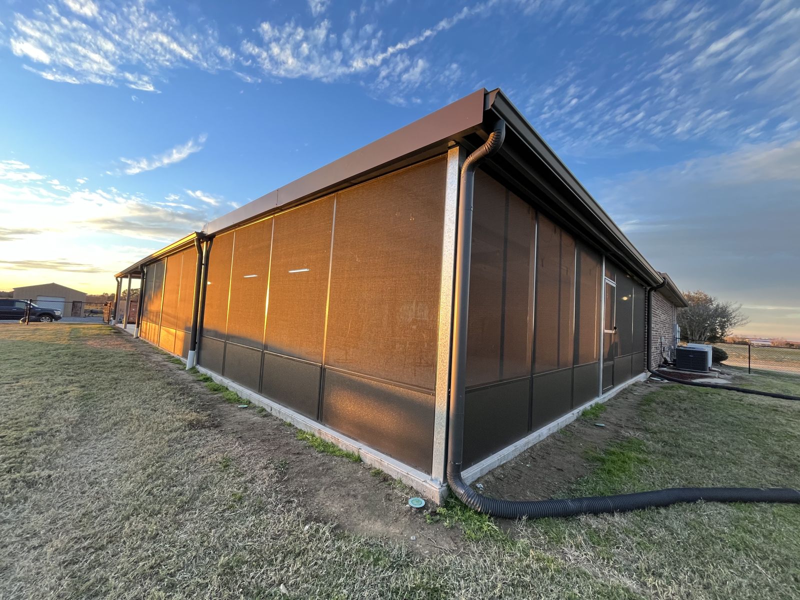 Long screened enclosure on a metal building at sunset