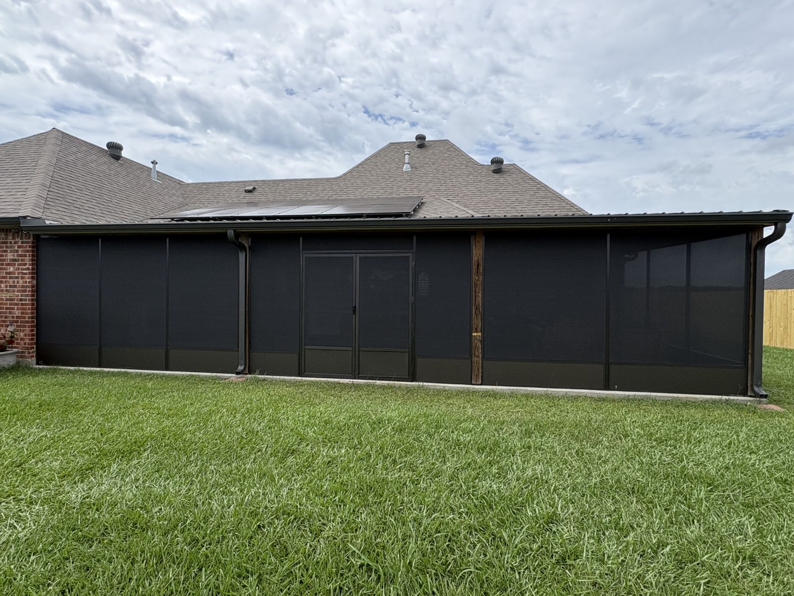 Long dark bronze screen room across the back of a home
