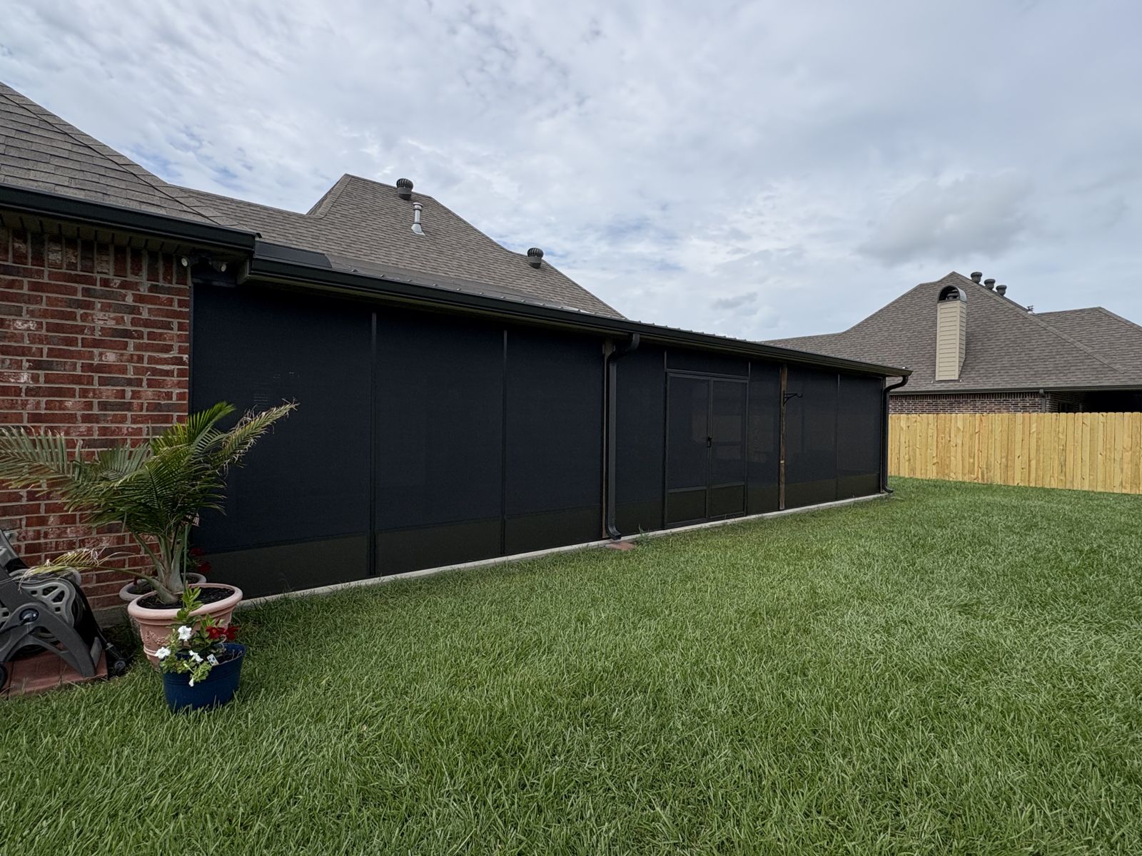 Side of a dark bronze screen room with a potted palm