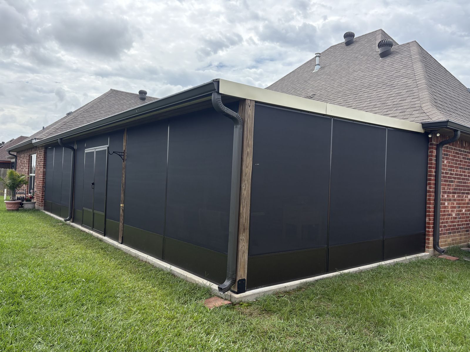 Dark bronze screen room wrapping the corner of a brick home