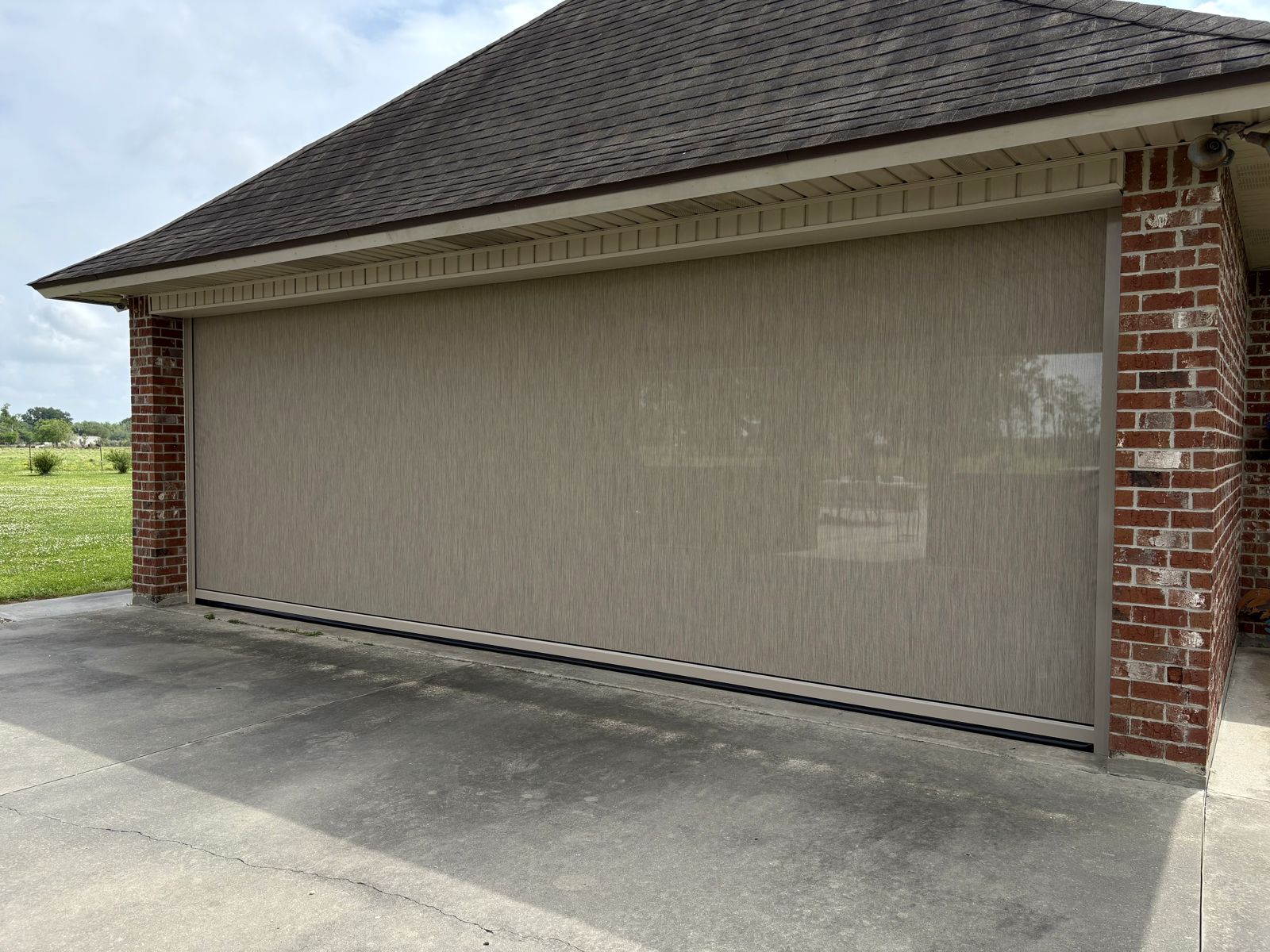 Tan motorized shade closing a wide garage-style patio opening