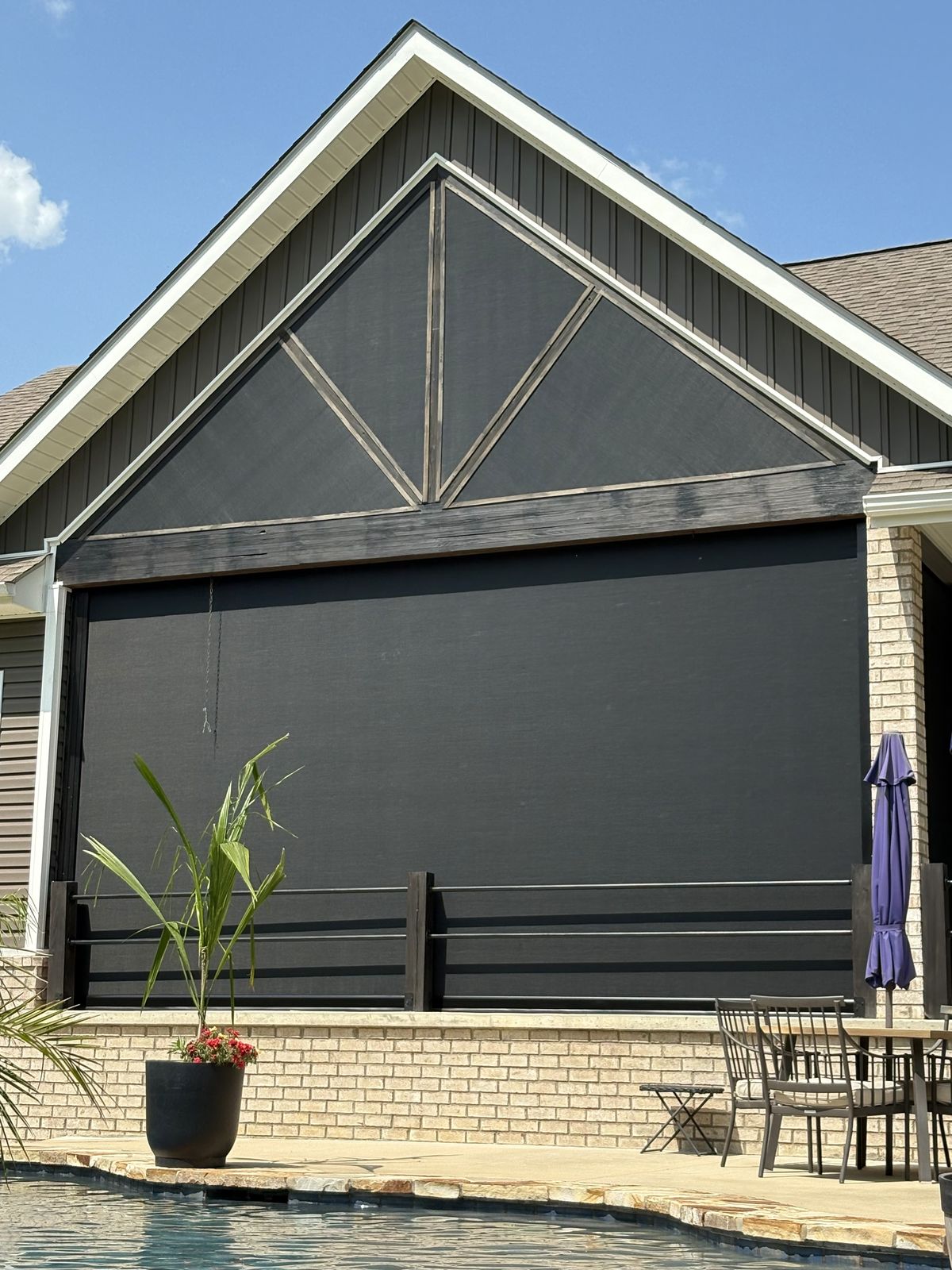 Tall black shade closing a gabled patio opening beside a pool