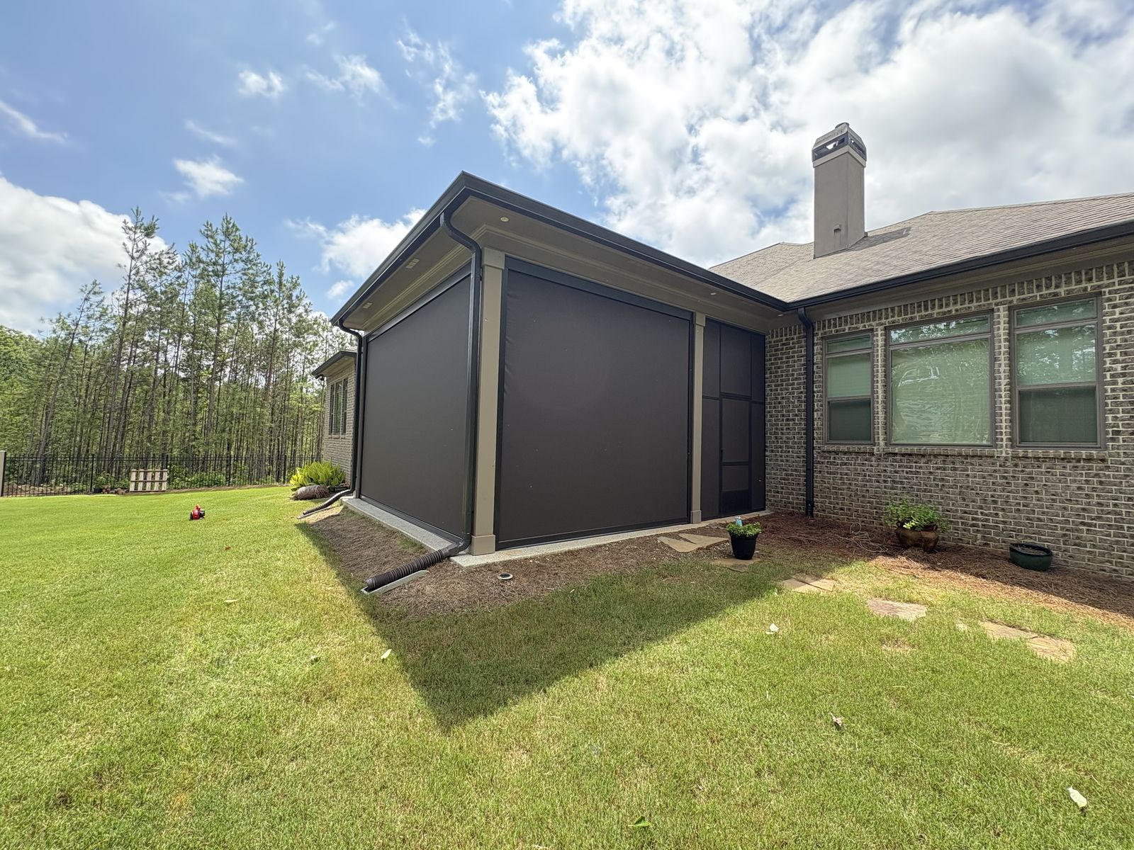Brown shades lowered along the back patio of a brick home