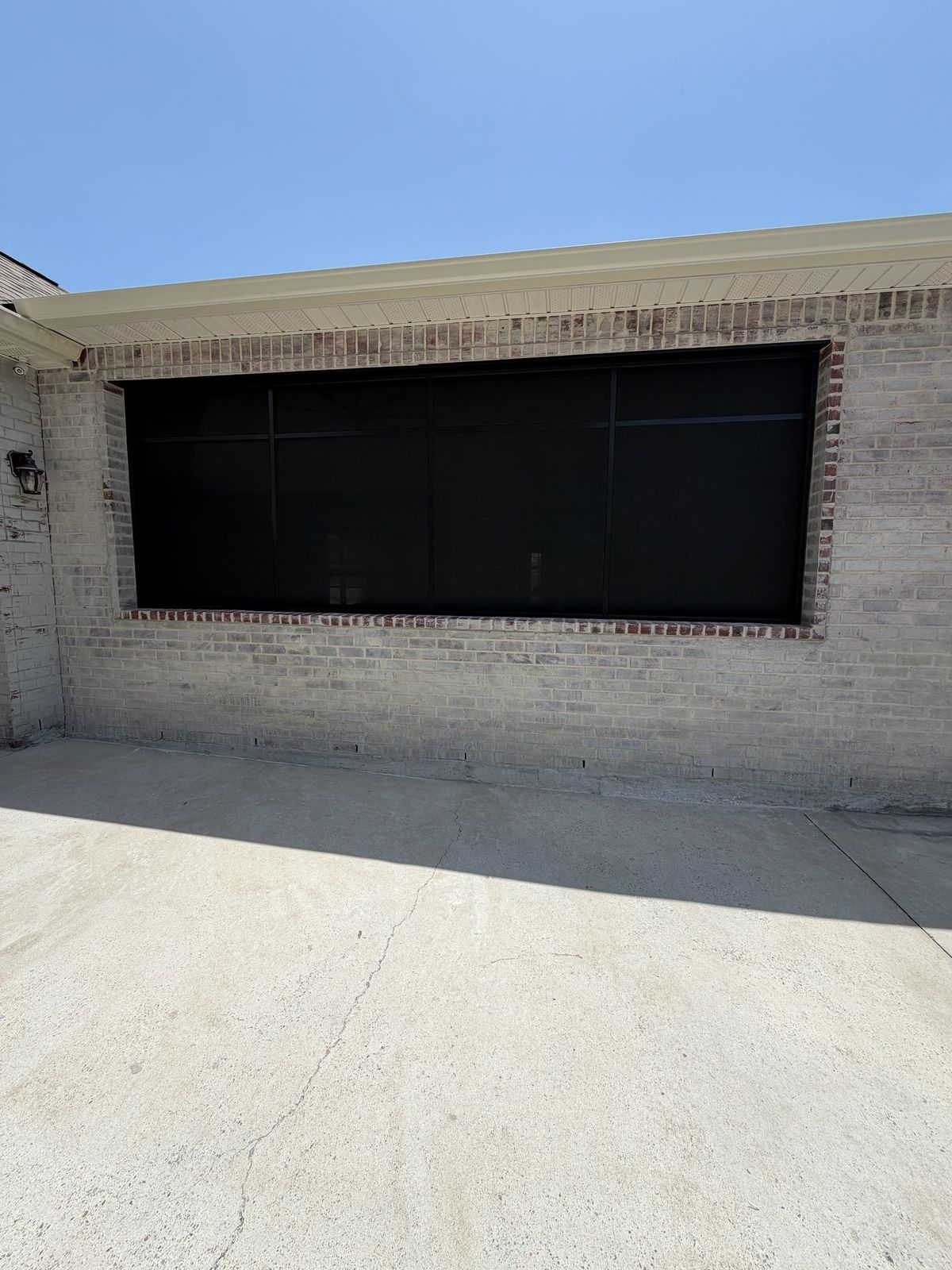 Dark screen panel filling a large opening on a light brick wall